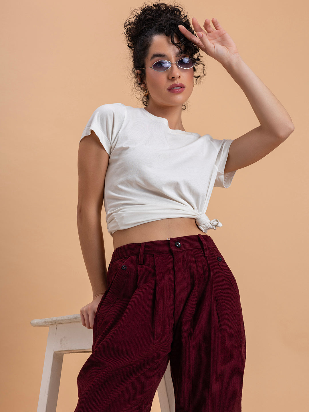 Detail of drawstring waistband and pocket on maroon corduroy trousers