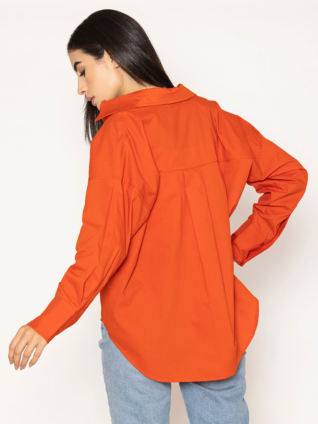 Lifestyle shot of woman wearing rust cotton poplin oversized shirt