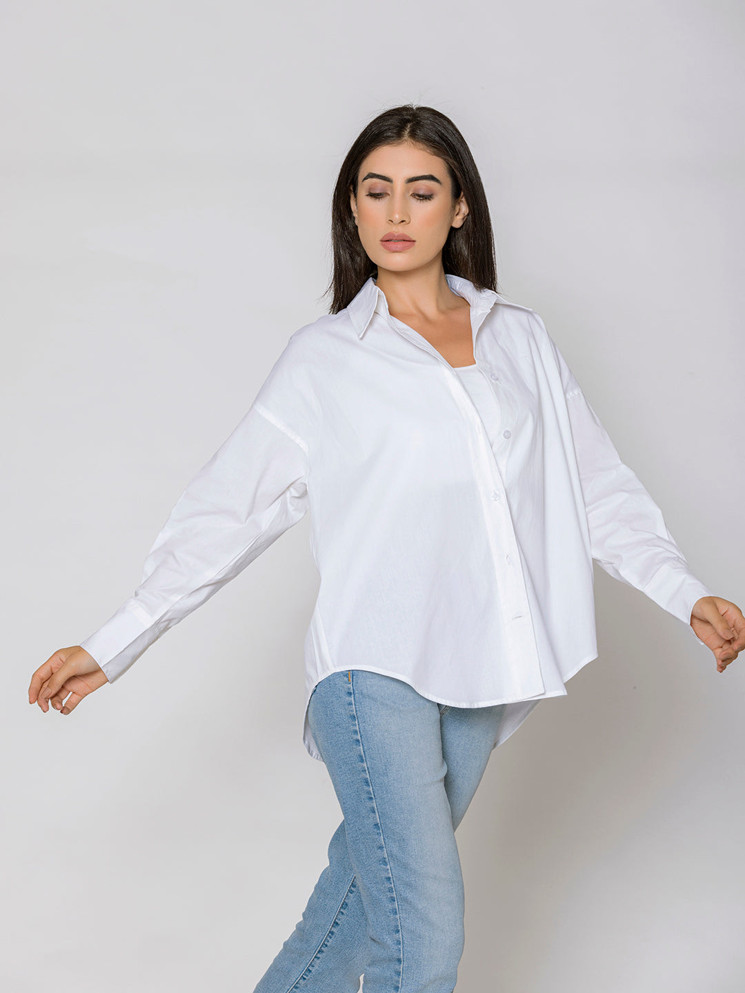 Lifestyle shot of woman in oversized white poplin shirt styled with brown trousers