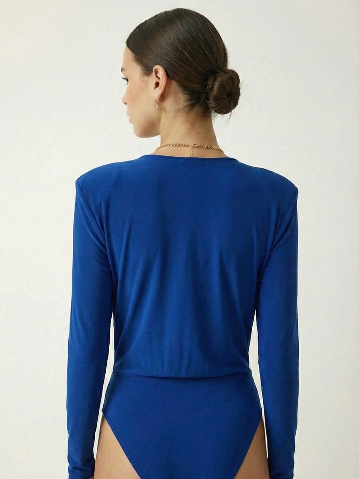 Lifestyle shot of royal blue V-neck bodysuit styled with denim