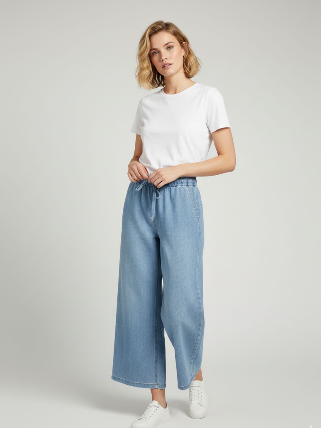 Close-up of drawstring waist on light blue denim trousers