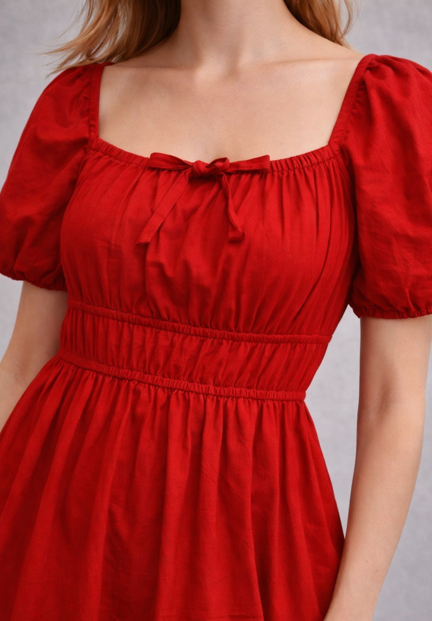 Lifestyle shot of model wearing red cotton smocked waist A-line dress