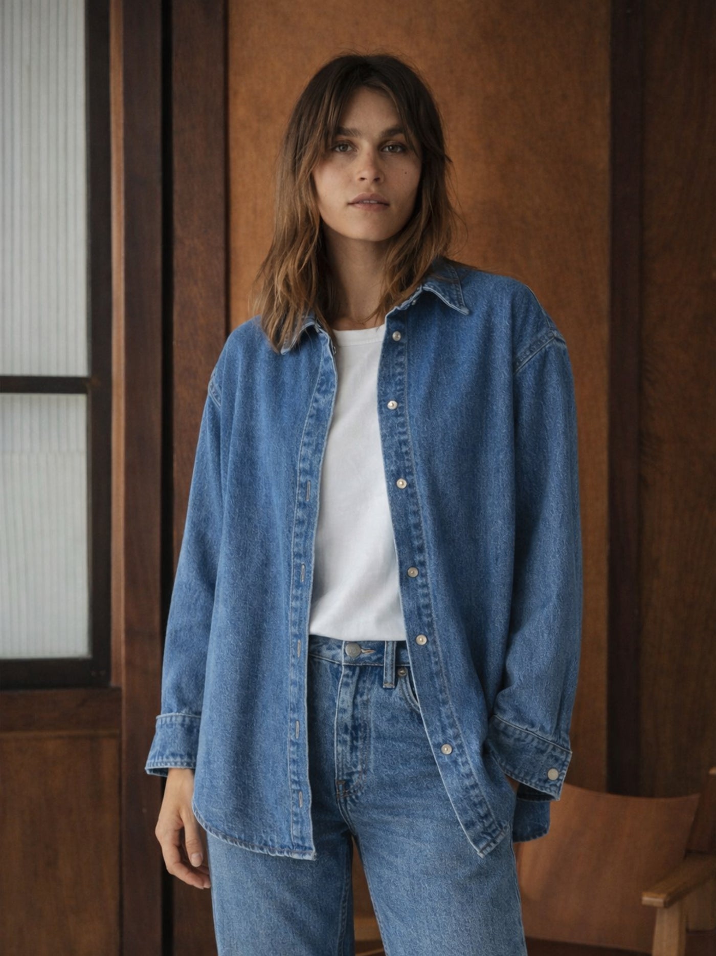 Back view of blue oversized denim shirt with curved hem