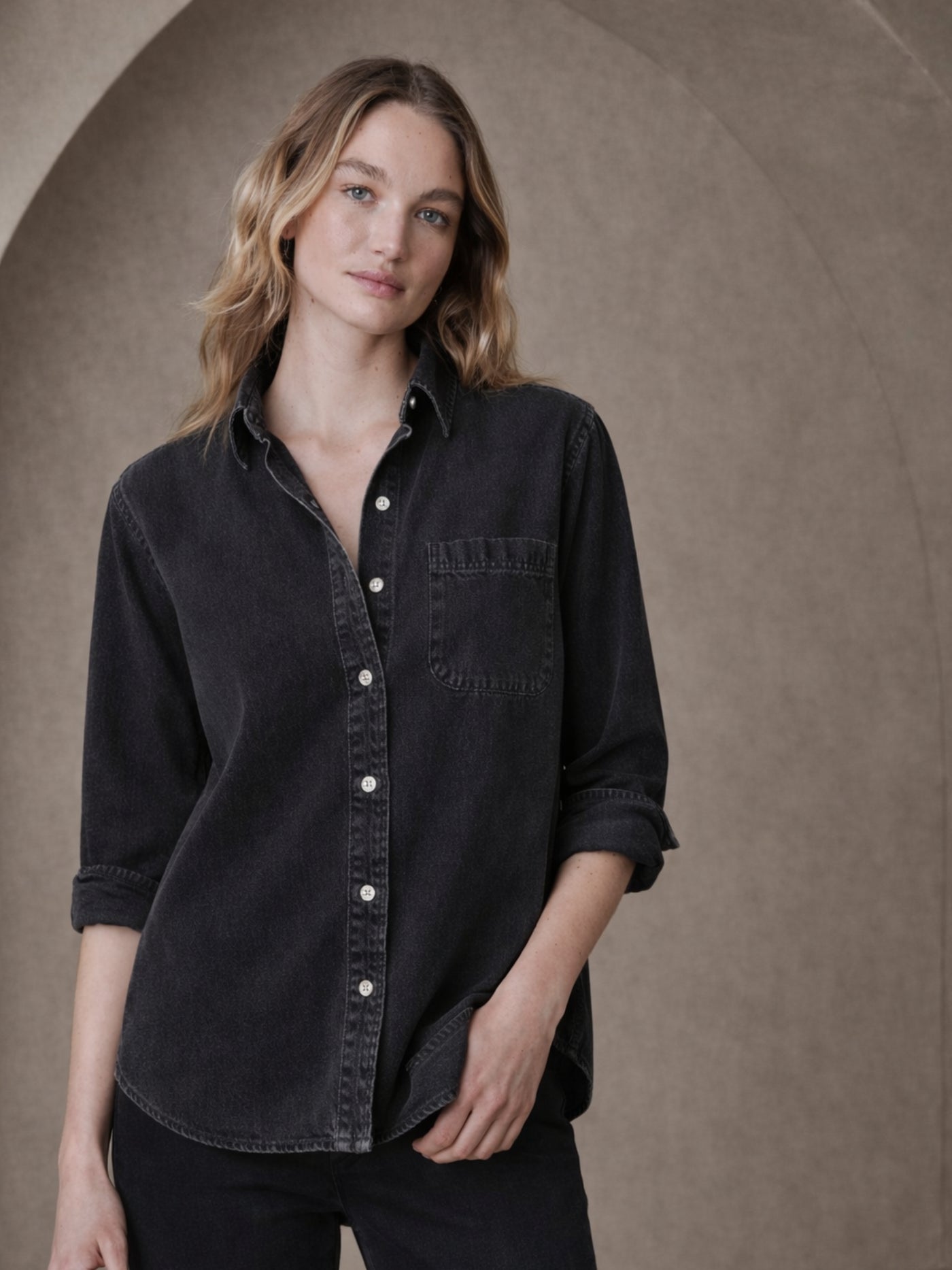 Back view of black oversized denim shirt with curved hem