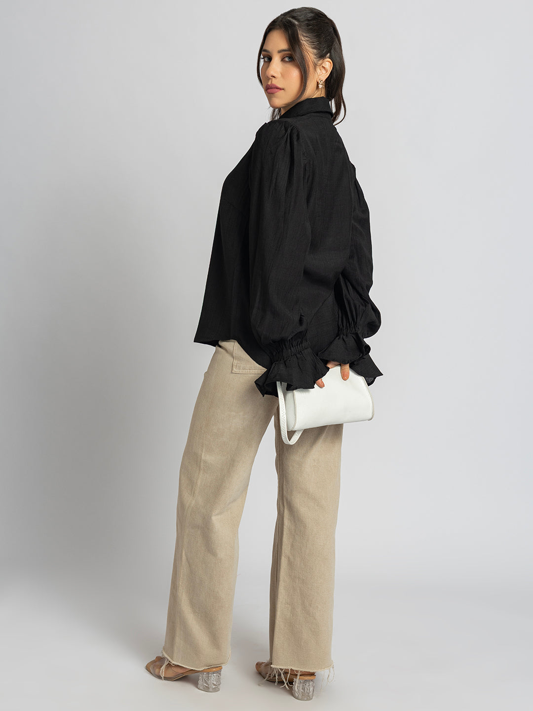 Back view of black ruffled cuff shirt with curved hem