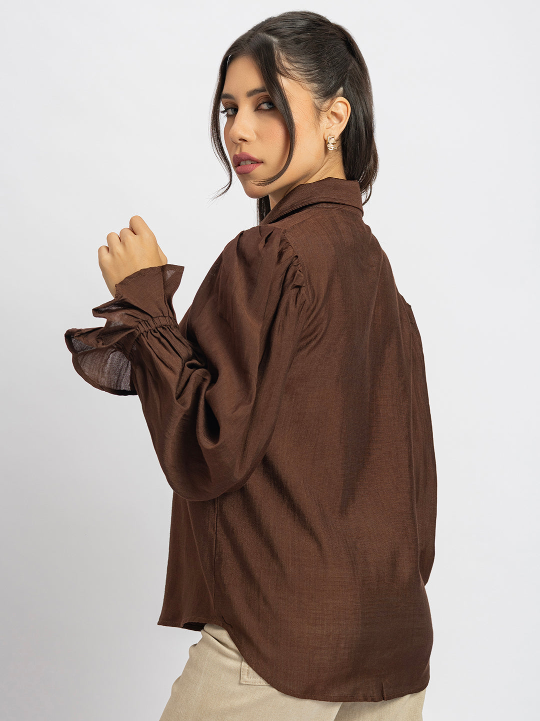 Lifestyle shot of woman wearing brown ruffled cuff shirt