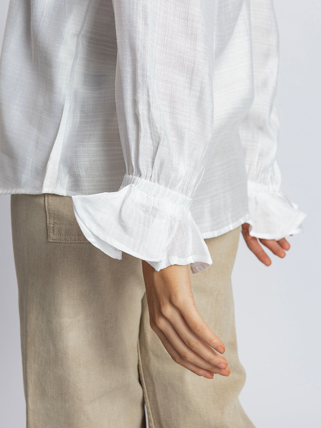 Back view of white ruffled cuff shirt with curved hem