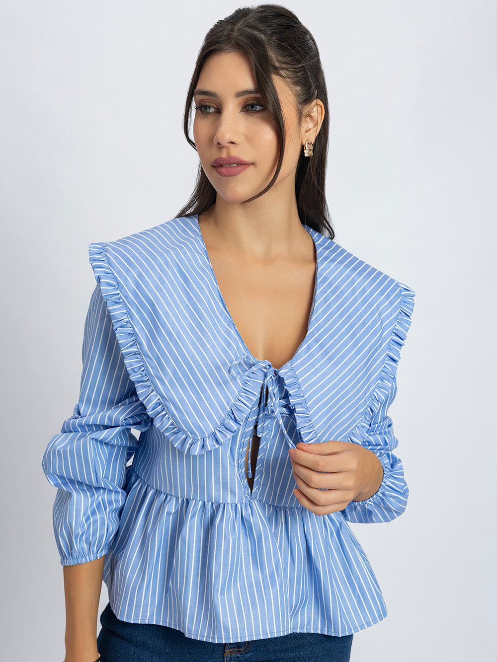 Side view of blue and white peplum top with frill collar