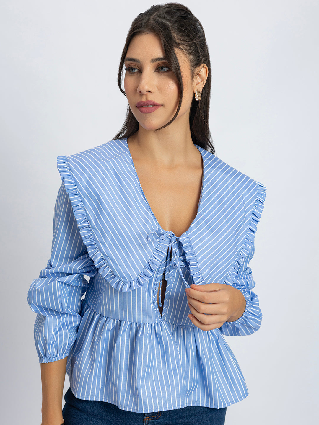Side view of blue and white peplum top with frill collar