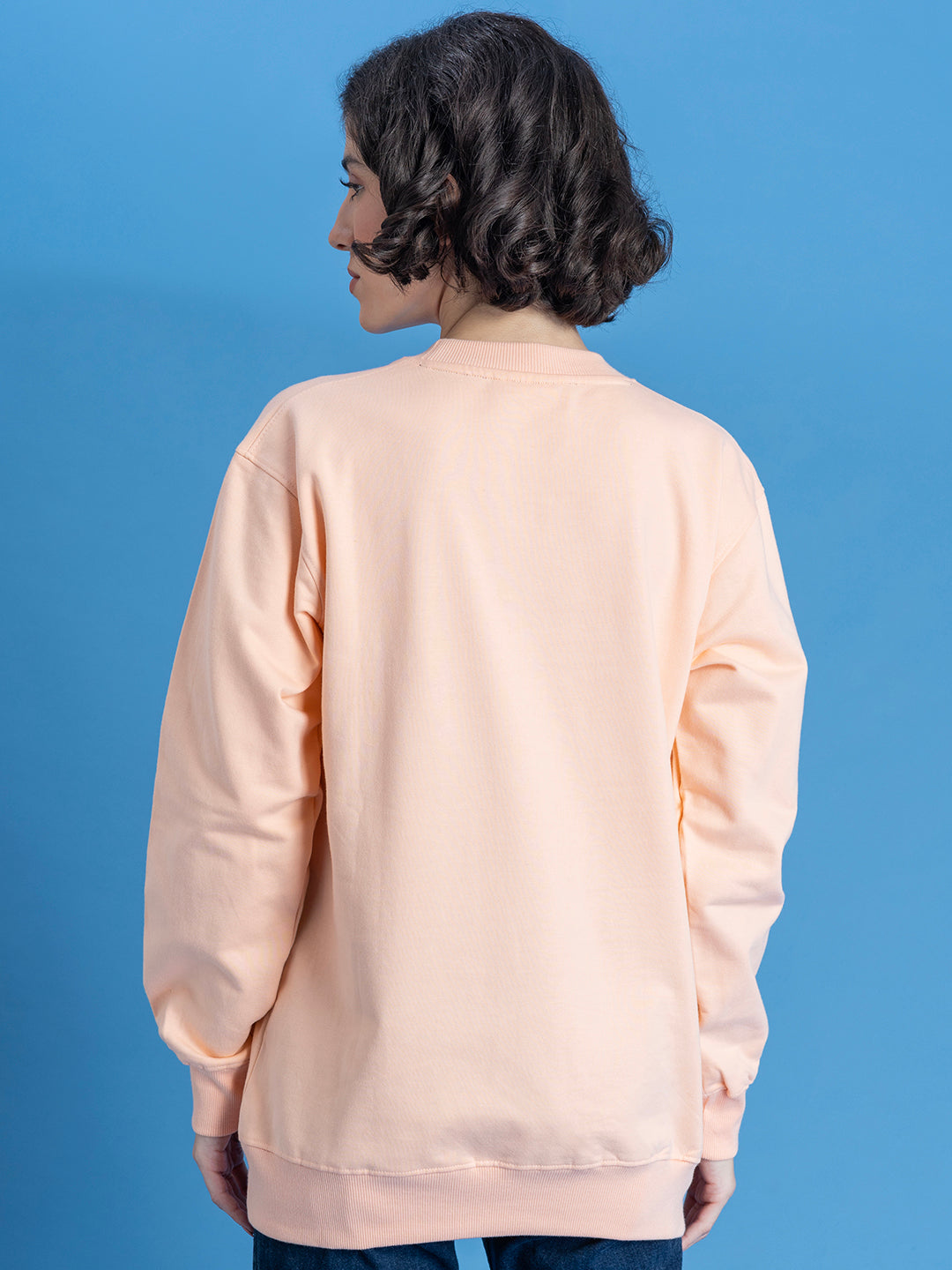 Lifestyle shot of peach sweatshirt styled with joggers