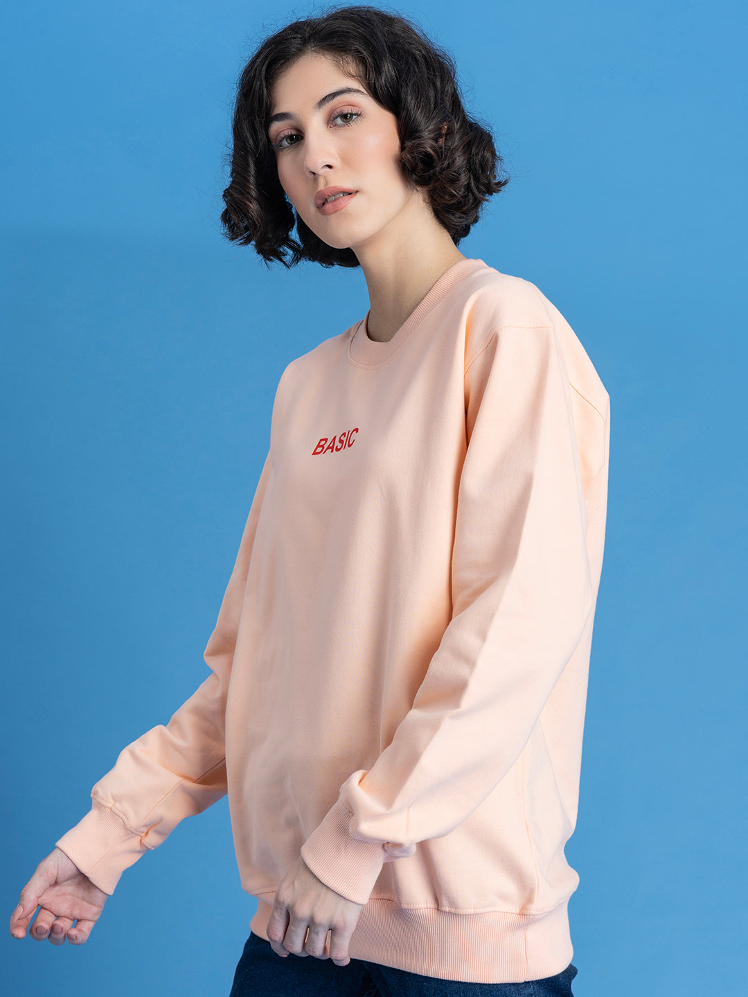 Model wearing peach sweatshirt in a relaxed casual look