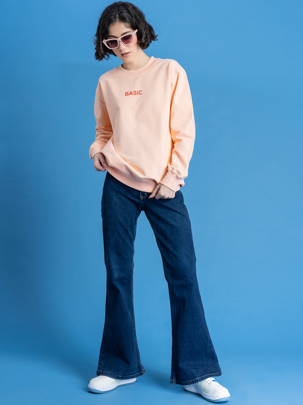 Side view of peach sweatshirt showing relaxed drop-shoulder fit