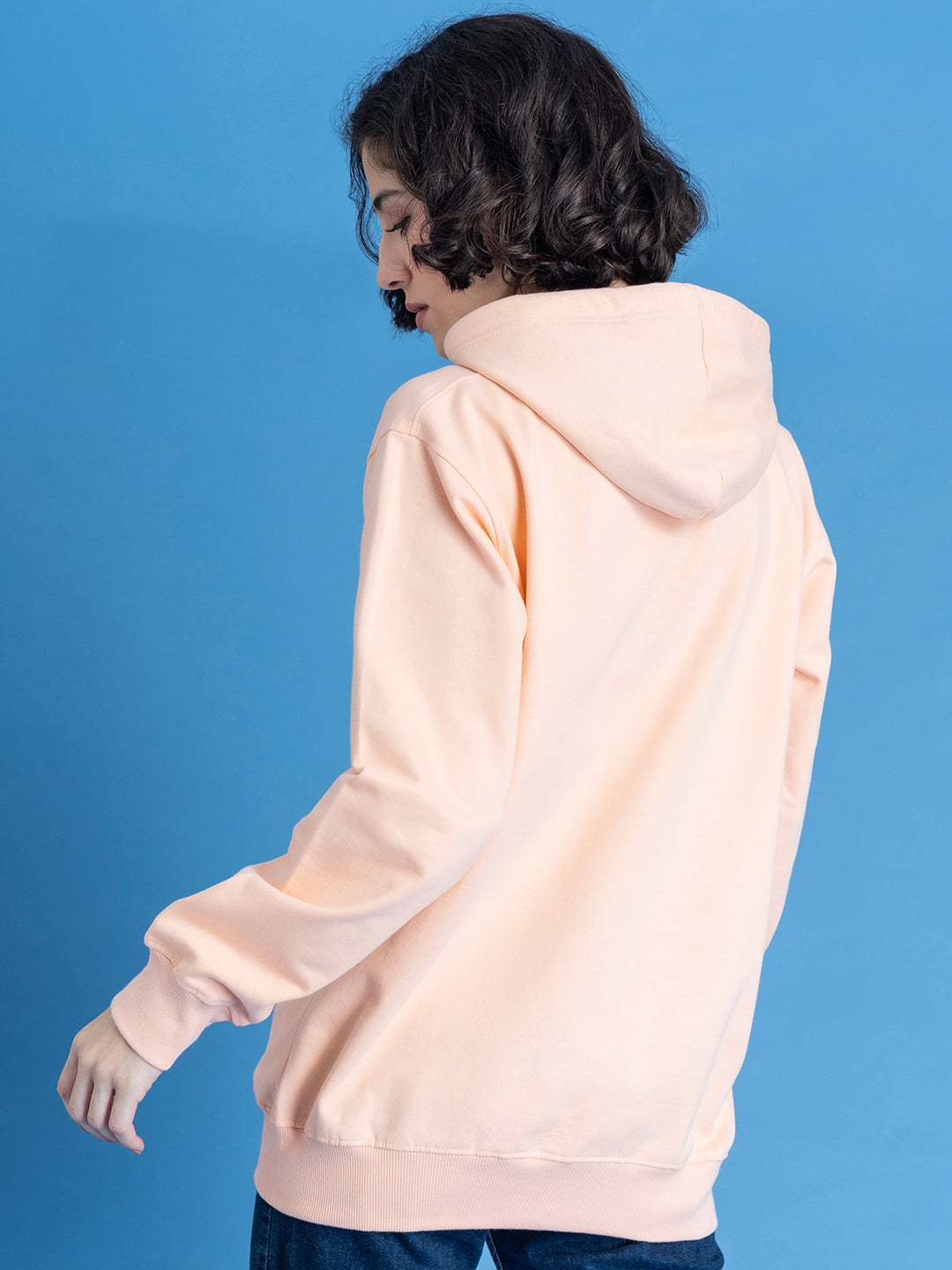 Lifestyle shot of peach hoodie styled with jeans