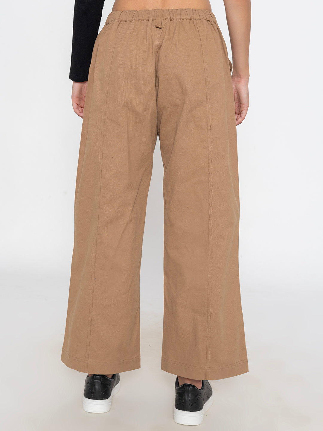 Beige cotton baggy trousers shown in soft daylight