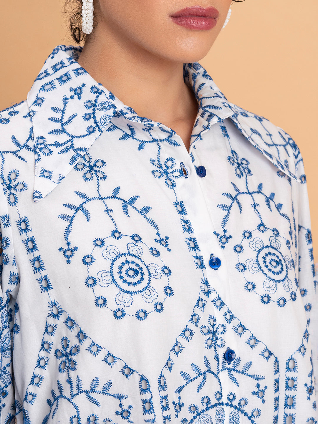 Detail of relaxed shorts with blue schiffli embroidery on white cotton