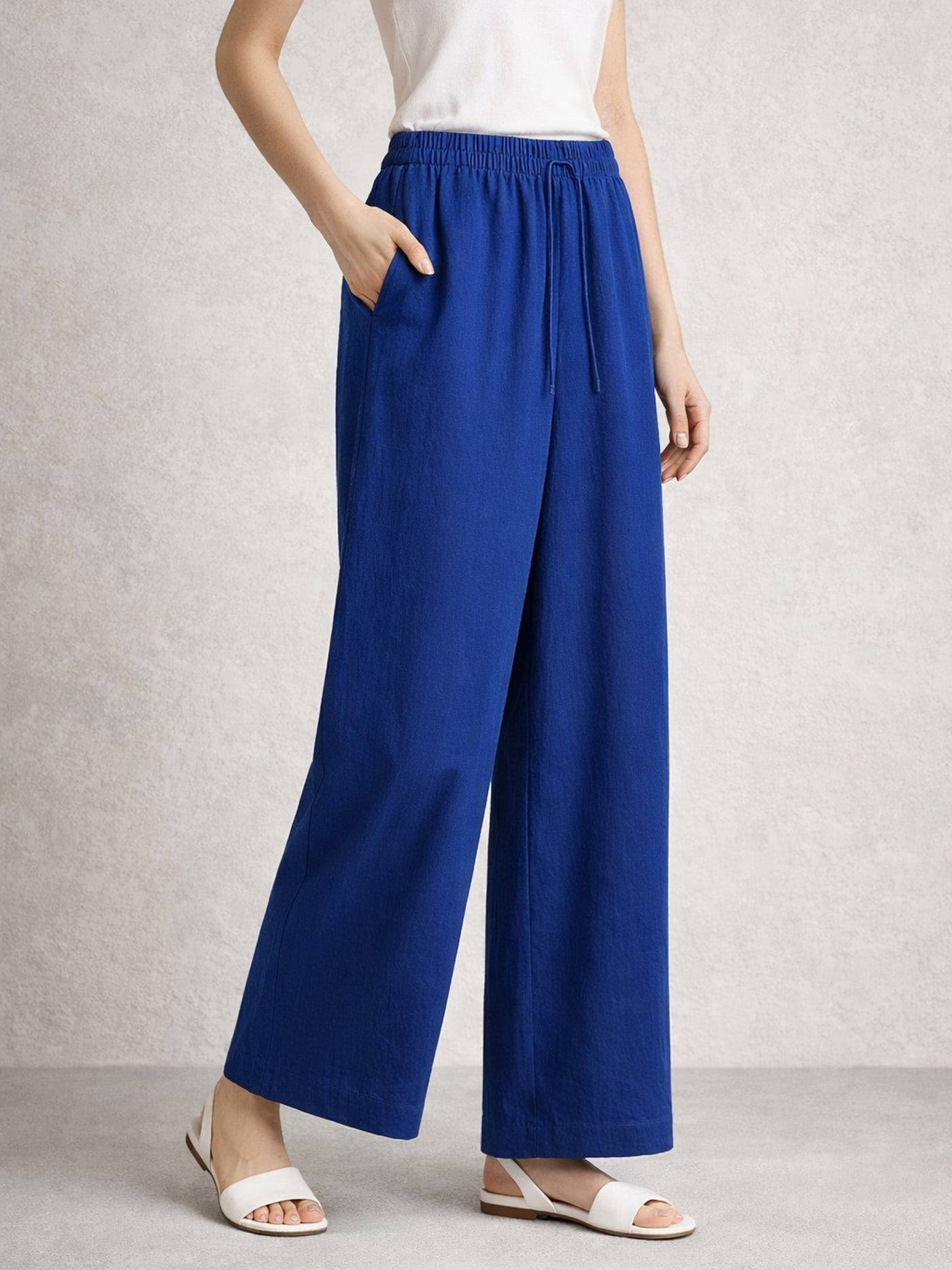 Detail of elasticated drawstring waist on blue baggy trousers