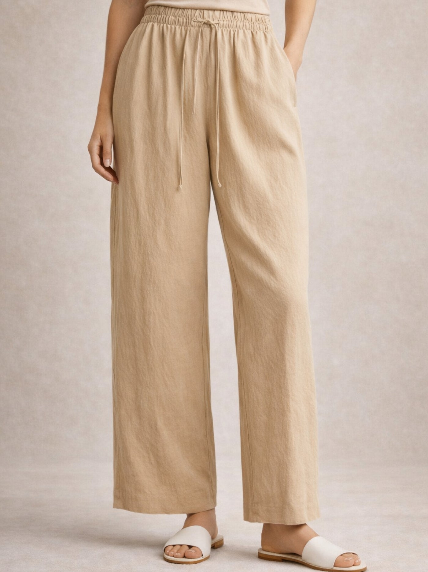 Detail of elasticated drawstring waist on beige baggy trousers