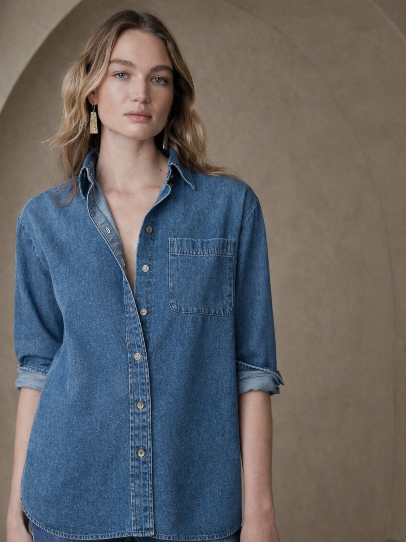 Back view of blue oversized denim shirt with curved hem