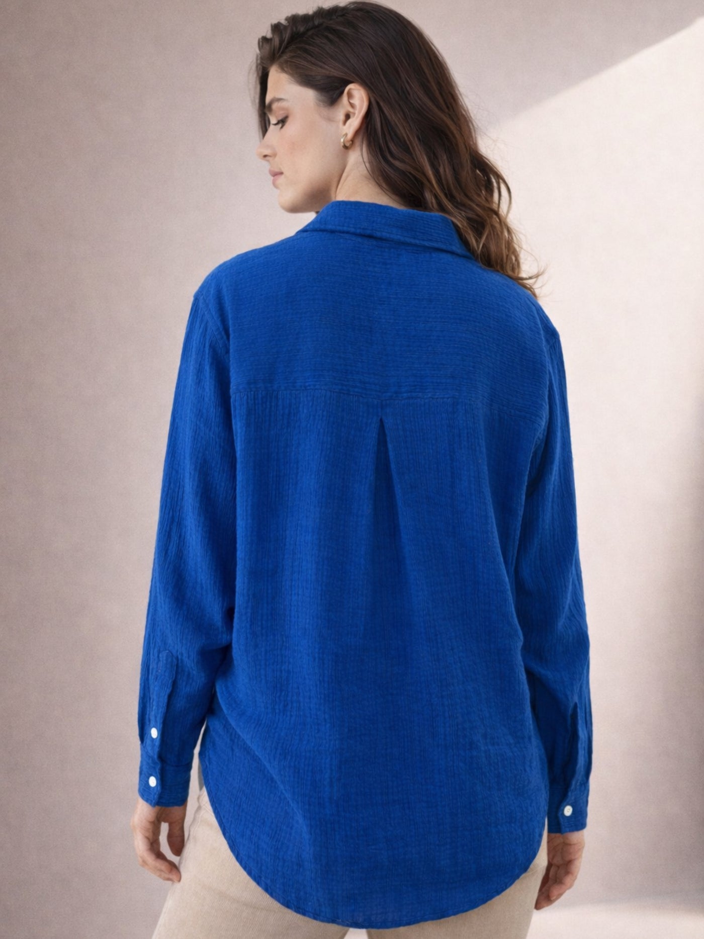 Lifestyle shot of woman wearing blue wrinkled cotton shirt