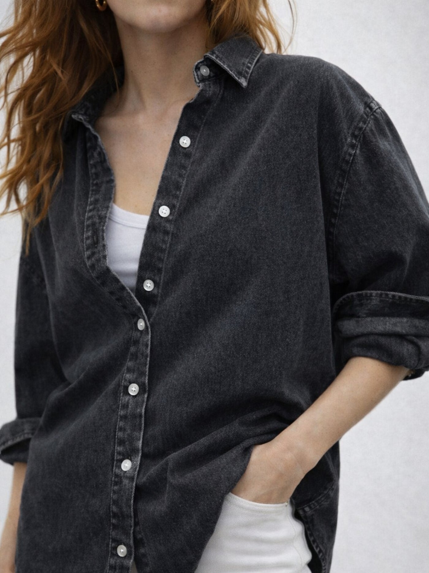 Back view of black oversized denim shirt with curved hem