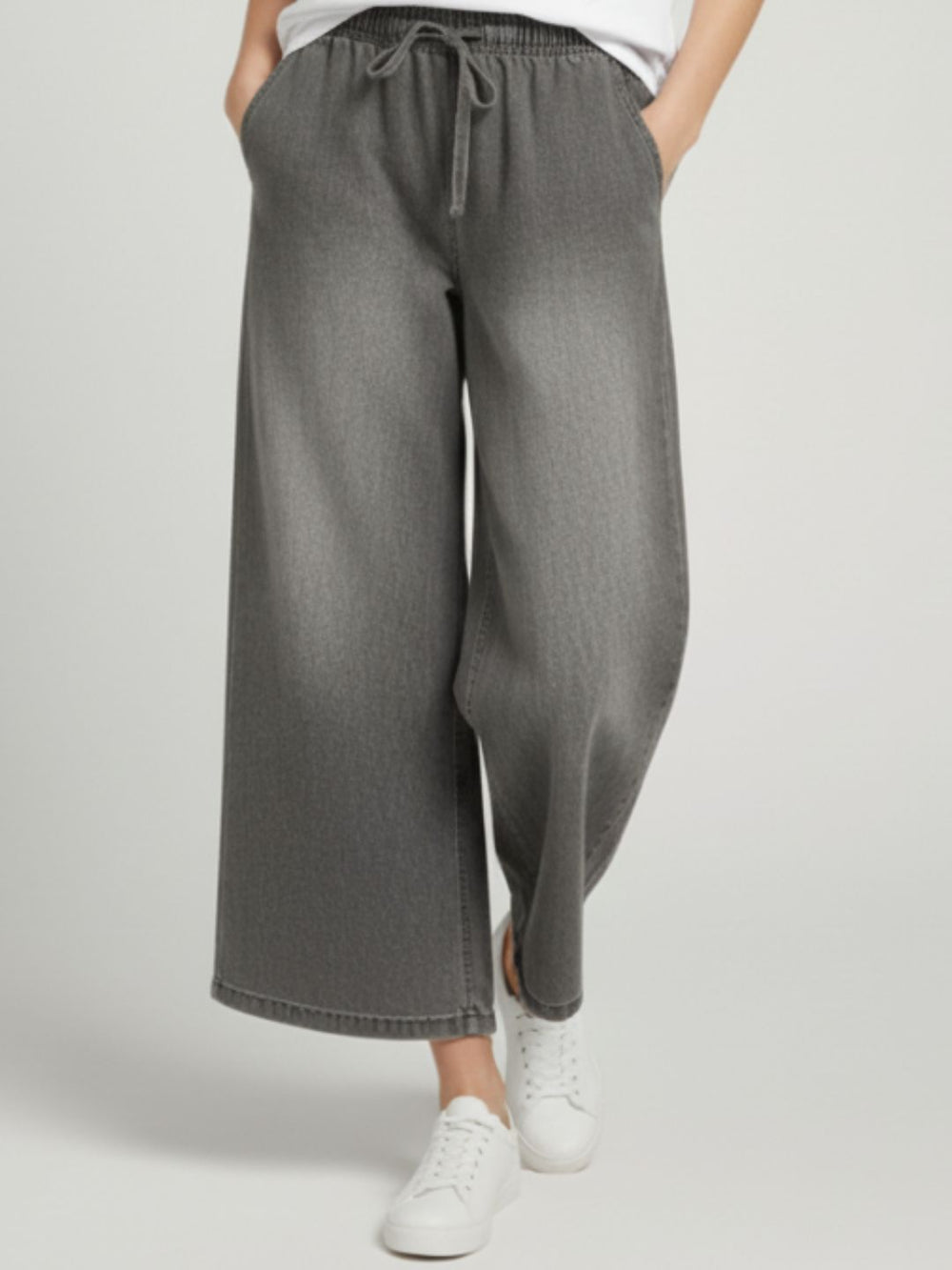 Side view of mid-rise grey drawstring trousers showing pocket detail