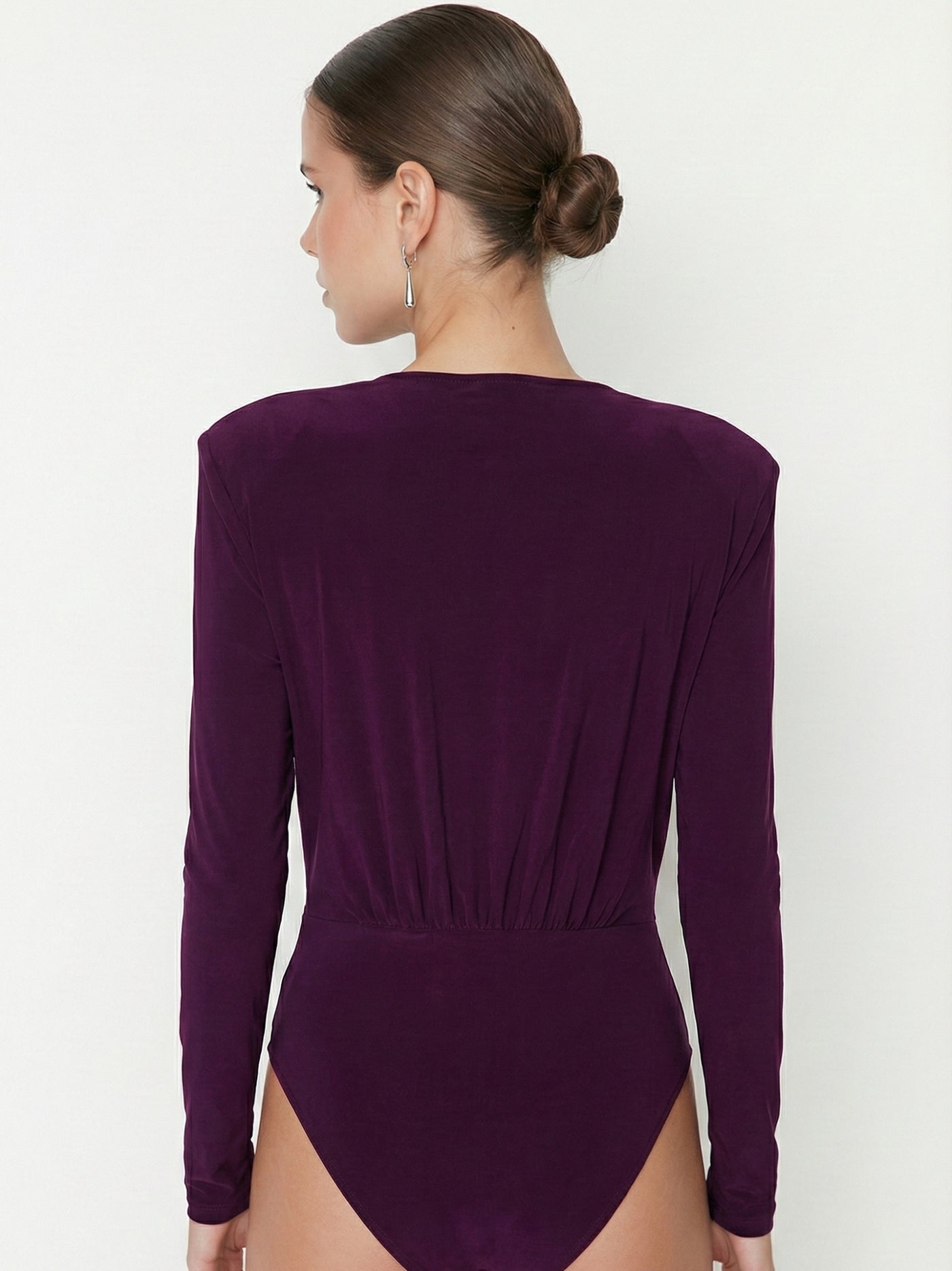 Lifestyle shot of maroon V-neck bodysuit styled with denim