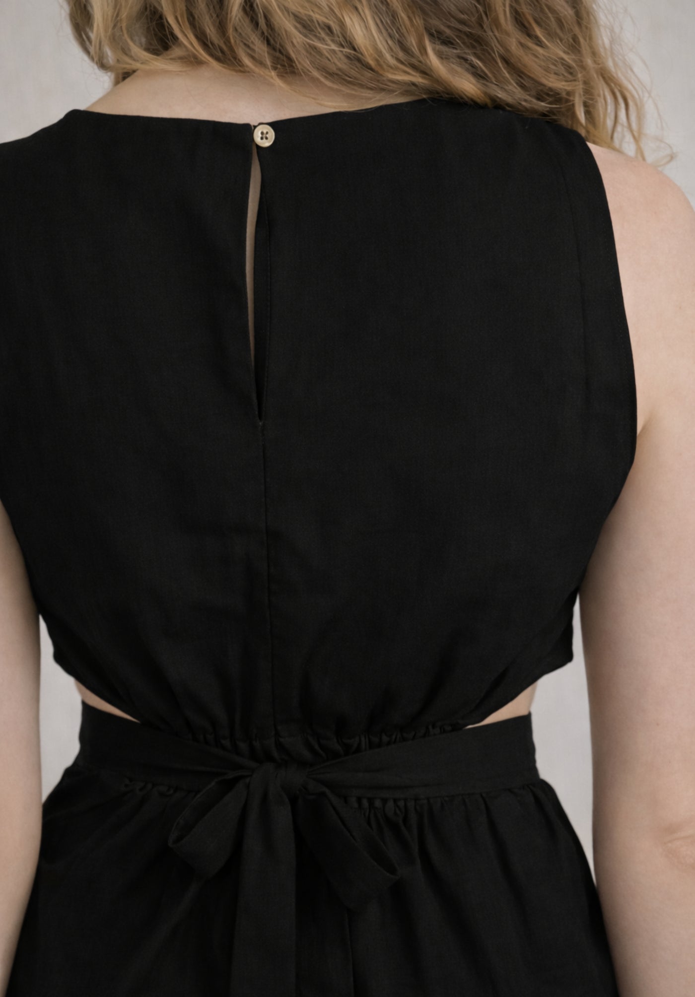Lifestyle shot of woman wearing black A-line cotton dress