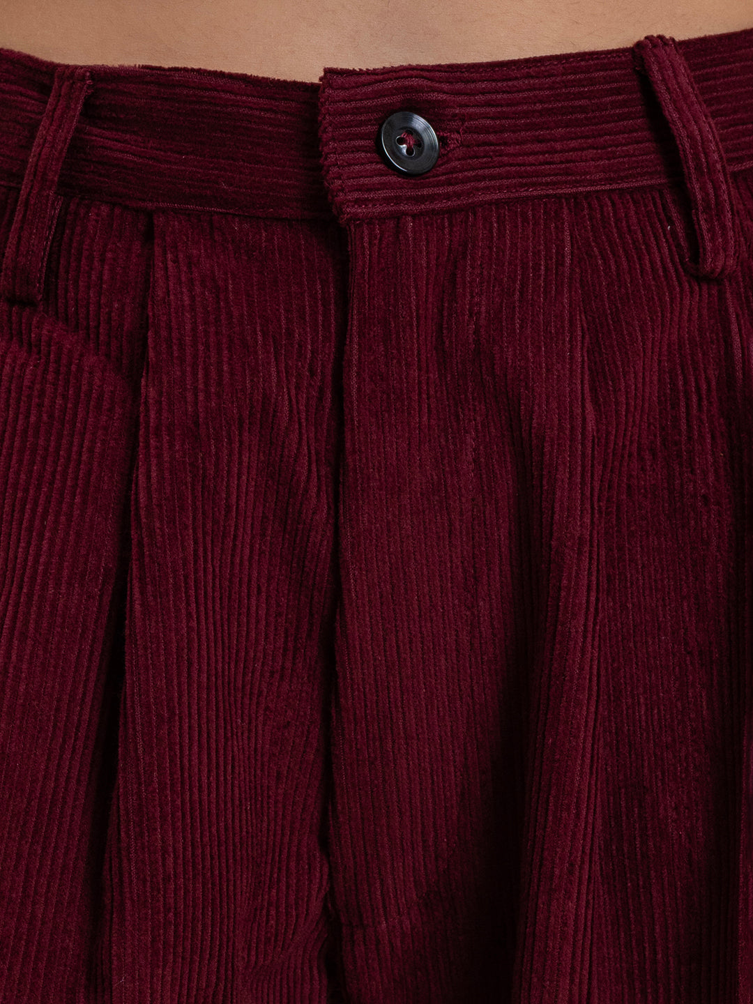 Close-up of corduroy fabric texture on maroon baggy trousers