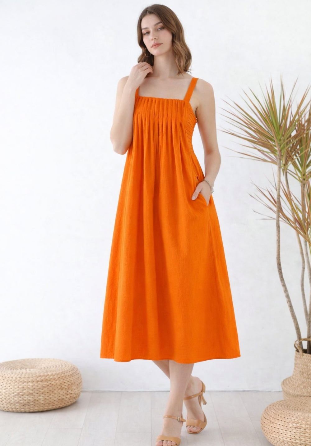 Side view of rust pleated cotton A-line midi dress with smocked waist