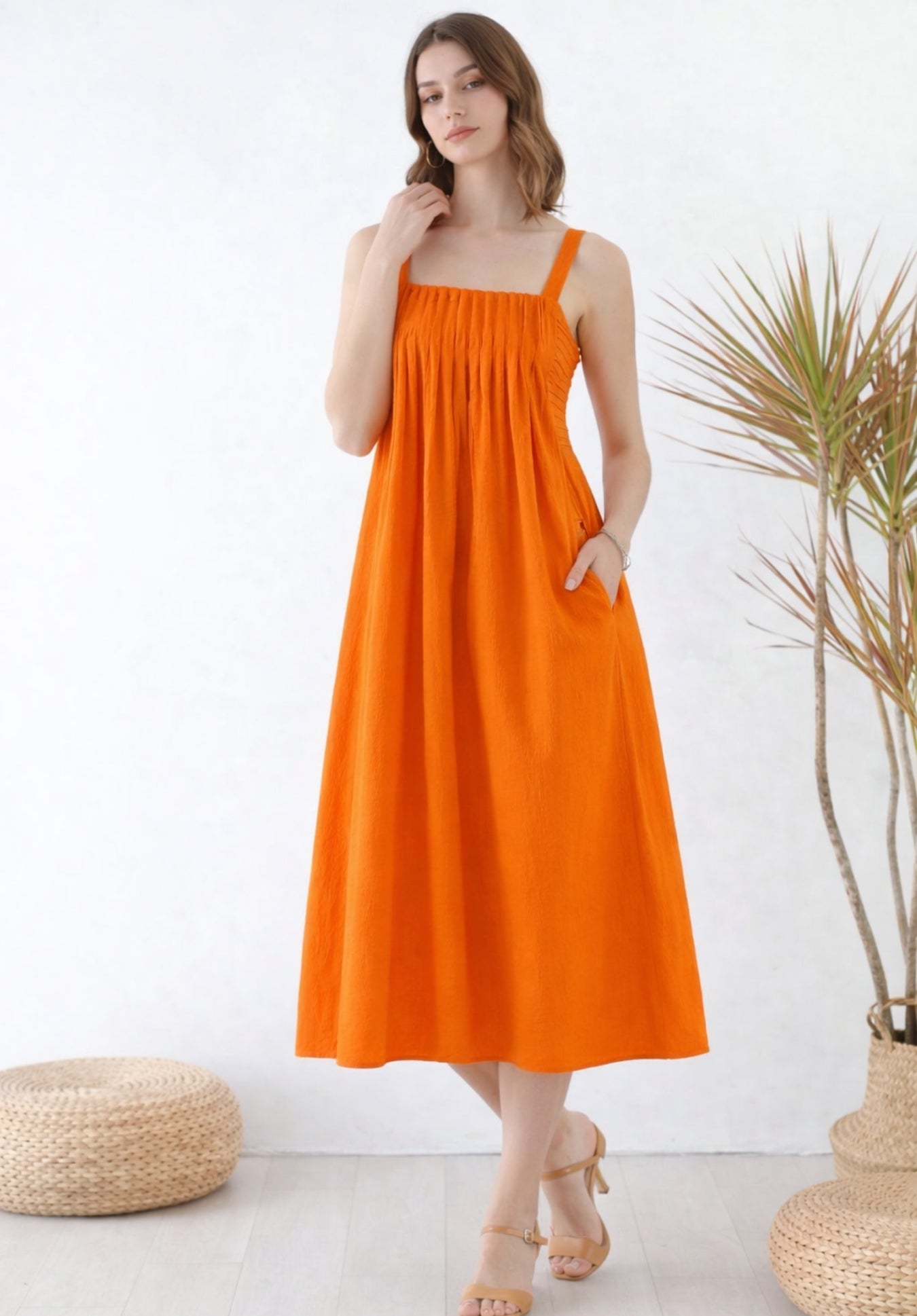 Side view of rust pleated cotton A-line midi dress with smocked waist
