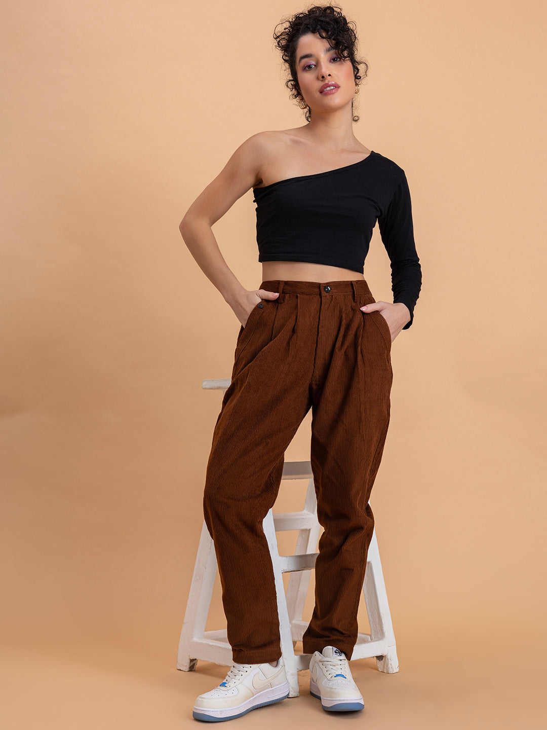 Detail of drawstring waistband and pocket on brown corduroy trousers