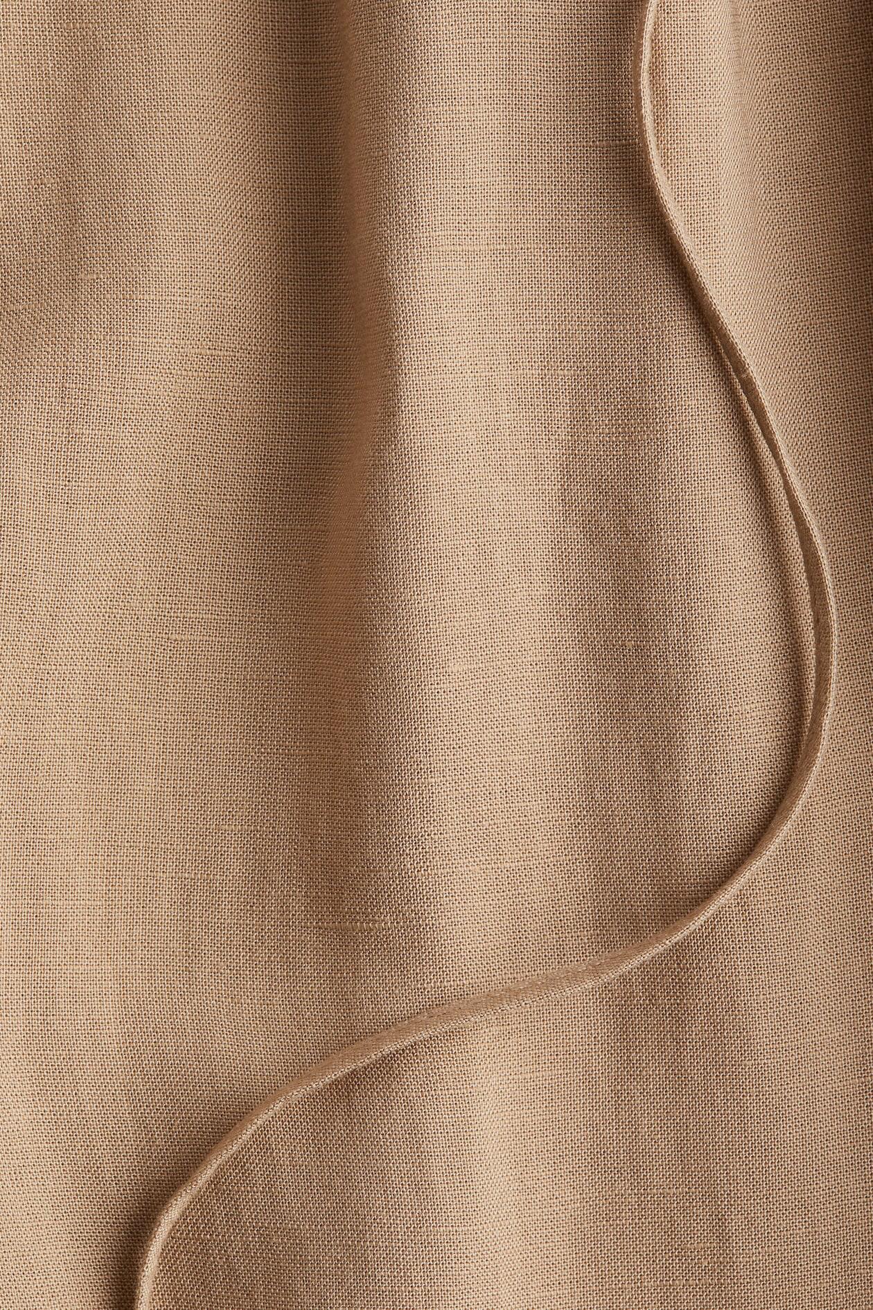 Back view of beige baggy trousers with relaxed straight legs