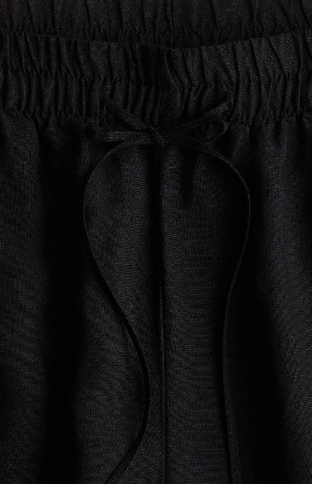 Side view of black baggy trousers with drawstring waist