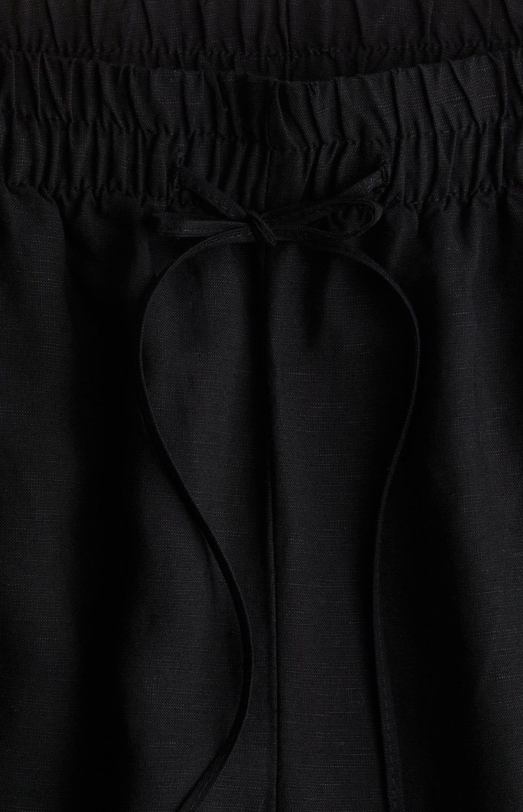 Side view of black baggy trousers with drawstring waist